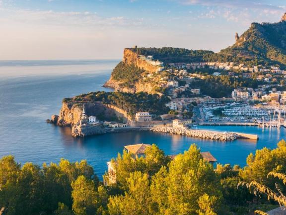 View over the harbour entrance of Port de Soller in Mallorca with its rocky shore and blue water.
