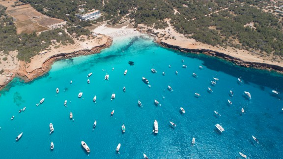 many boats over turquoise sea and small cliff. Cala Saona in Formentera island.
